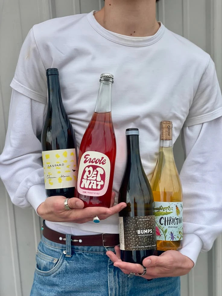 Vier Naturweinflaschen in den Händen: Chenin Blanc, Pét-Nat, Sauvignon Blanc und Orange Wine